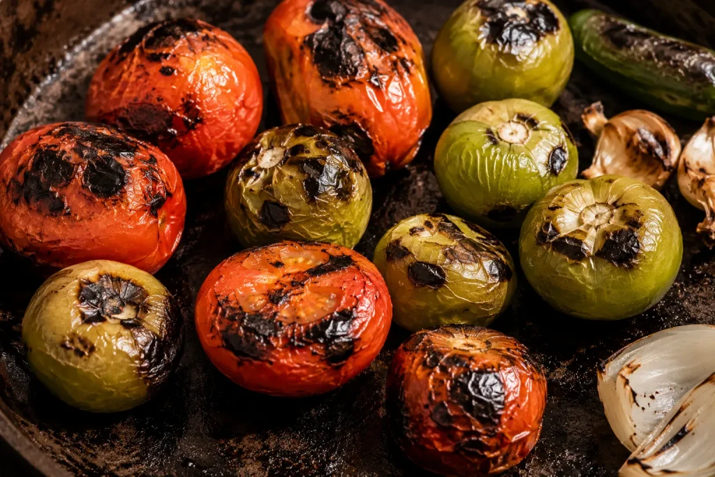 Tomatoes and tomatillos roasting on traditional Mexican comal